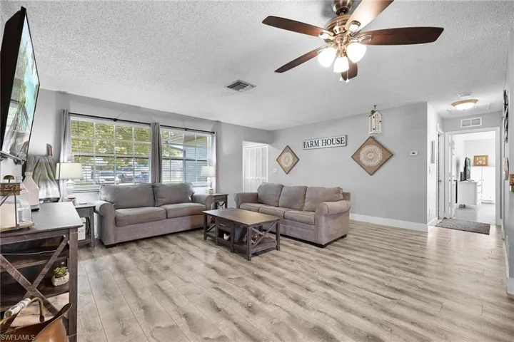 Living room featuring light wood-type flooring, a textured ceiling, and ceiling fan