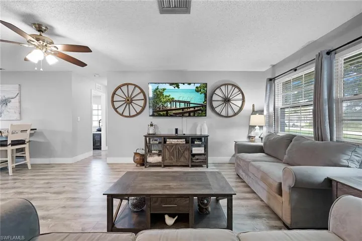 Living room with ceiling fan, light hardwood / wood-style floors, and a textured ceiling