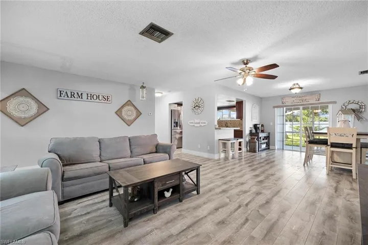 Living room featuring ceiling fan, sink, a textured ceiling, and light hardwood / wood-style flooring