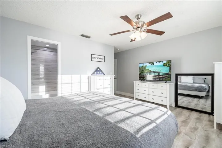 Bedroom featuring a textured ceiling, light hardwood / wood-style flooring, ceiling fan, and ensuite bathroom