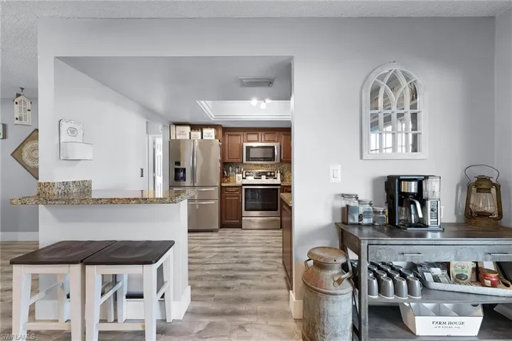 Kitchen featuring tasteful backsplash, a kitchen bar, stainless steel appliances, light stone countertops, and light hardwood / wood-style floors