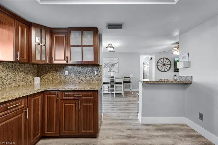 Kitchen featuring light stone counters, kitchen peninsula, and ceiling fan