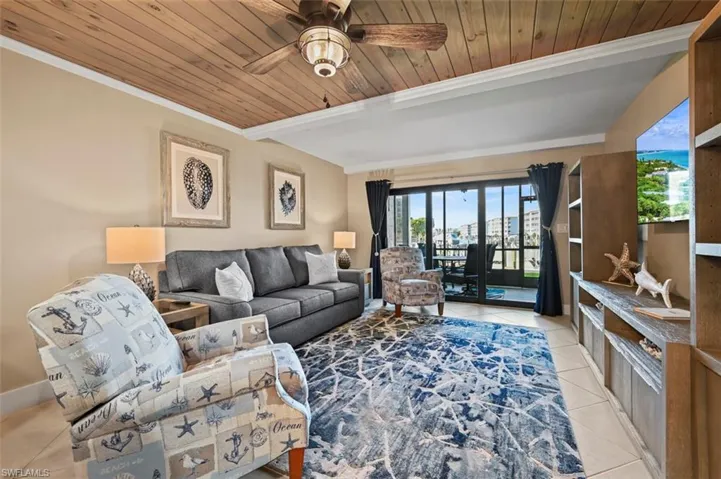 Living room featuring wood ceiling, light tile patterned floors, crown molding, and ceiling fan