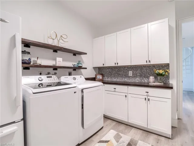 A laundry room designed with functionality in mind.  From floating shelves, built in cabinetry wood stained countertops and pebble-marble style backsplash.