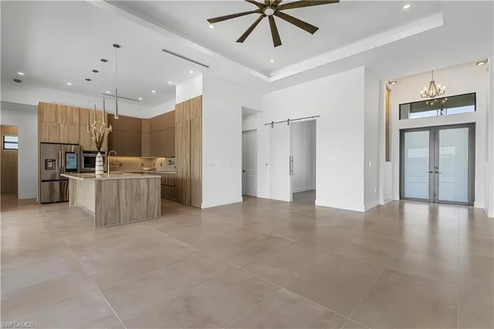 A striking COLUMNED FRONT PORCH with FLAT WOODEN CEILING welcomes you, framed by IMPACT-RESISTANT DOUBLE DOORS that open to an IMPRESSIVE FOYER accented with ACOUSTIC PANELING and designer lighting.