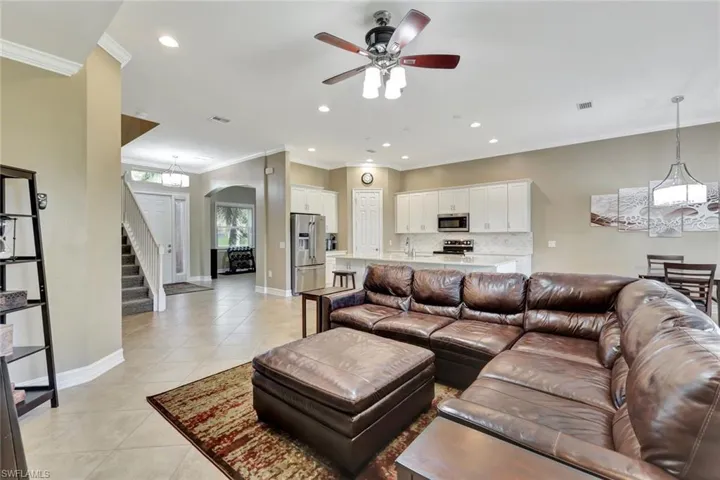 Living room with sink, ceiling fan, light tile patterned floors, and ornamental molding