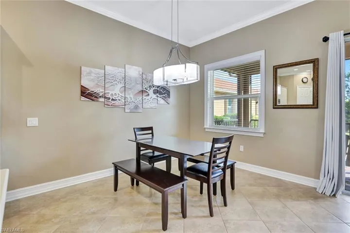 Tiled dining room featuring a chandelier and crown molding