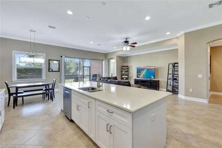 Kitchen with white cabinets, an island with sink, pendant lighting, sink, and stainless steel dishwasher