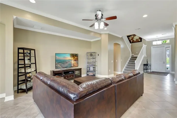 Living room with ceiling fan, ornamental molding, and light tile patterned floors