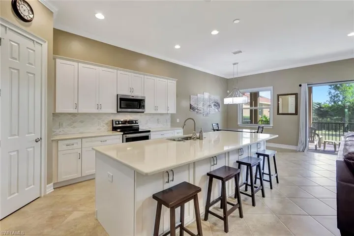 Kitchen featuring sink, white cabinetry, a kitchen island with sink, a breakfast bar, and appliances with stainless steel finishes