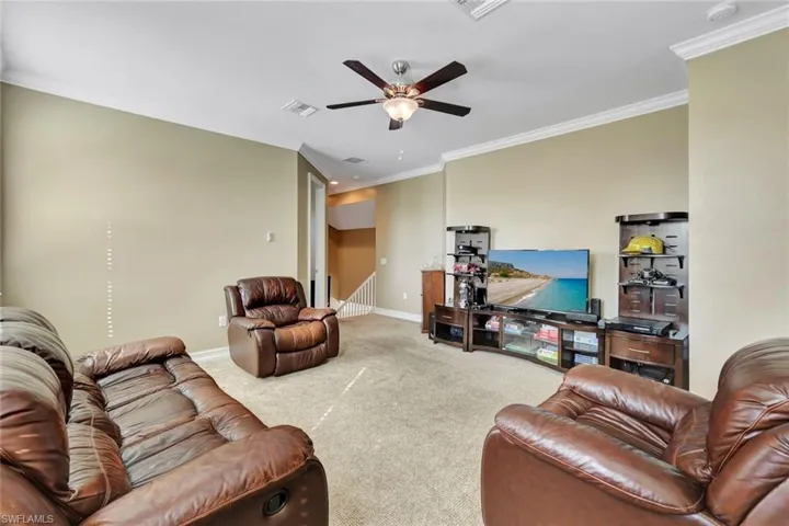 Living room with ceiling fan, carpet floors, and ornamental molding