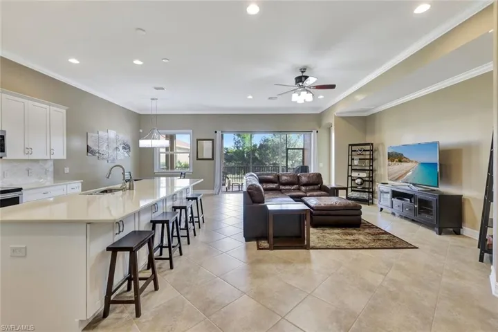 Living room with crown molding, ceiling fan, light tile patterned floors, and sink