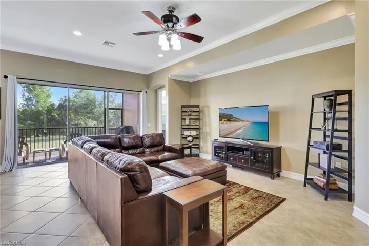 Tiled living room with ceiling fan and crown molding
