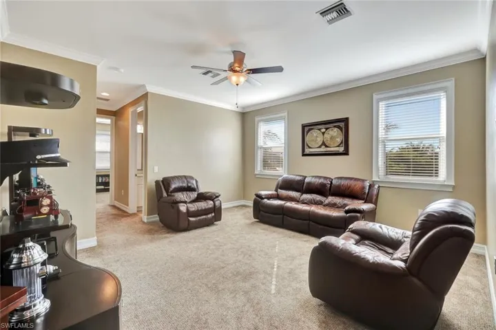 Carpeted living room with ornamental molding and ceiling fan