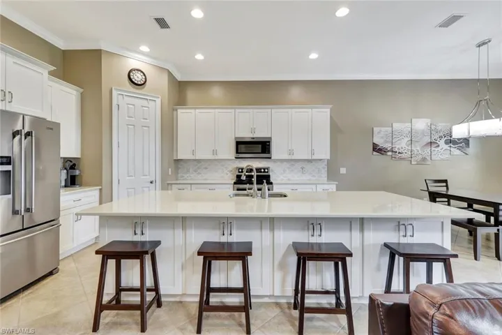 Kitchen with stainless steel appliances, sink, white cabinets, an island with sink, and pendant lighting