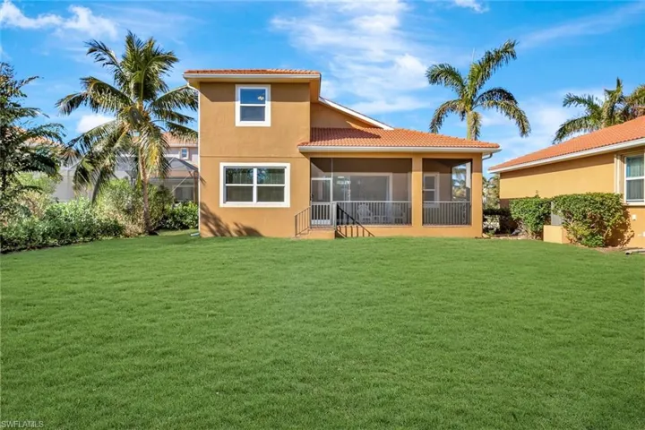 Rear view of house with a lawn and a sunroom