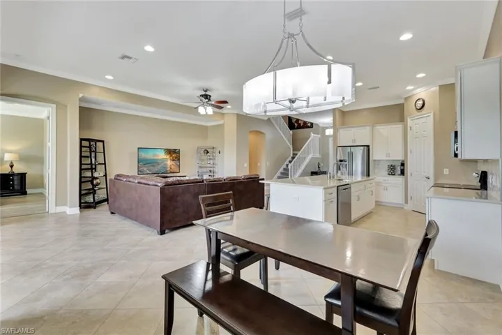 Tiled dining space with ceiling fan and crown molding