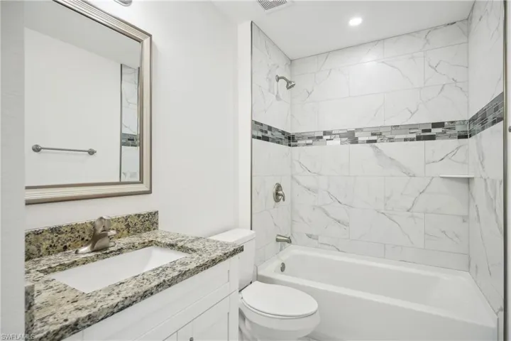 Guest bathroom with tile up to ceiling/ bath, vanity, and toilet