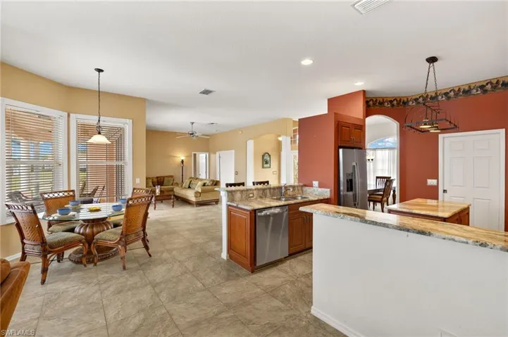 Kitchen featuring hanging light fixtures, light stone counters, appliances with stainless steel finishes, and recessed lighting