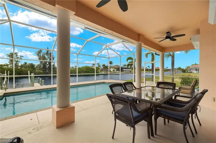 View of patio / terrace featuring a ceiling fan, glass enclosure, a water view, a sunroom, and an outdoor pool