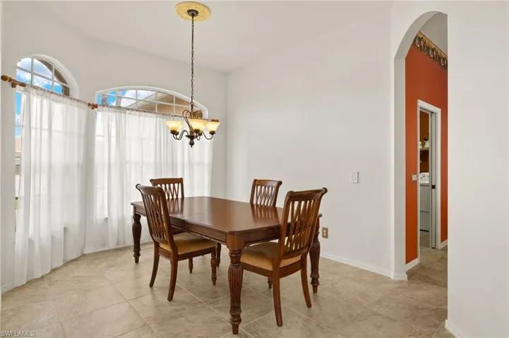 Dining area with arched walkways, a chandelier, and light tile patterned floors