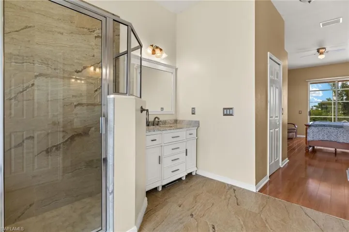 Bathroom with a marble finish shower, vanity, ensuite bath, light wood-style flooring, and a ceiling fan