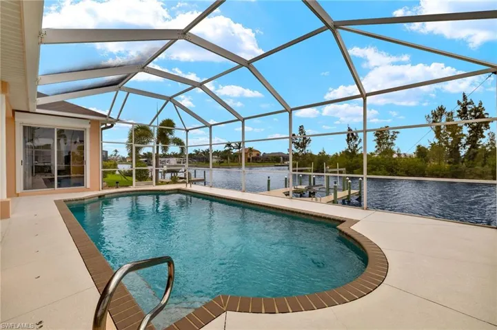 Swimming pool featuring a boat dock, boat lift, a water view, a sunroom, and glass enclosure