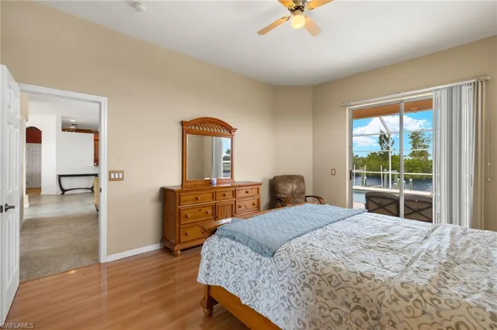 Bedroom featuring access to outside, light wood finished floors, a water view, a ceiling fan, and arched walkways