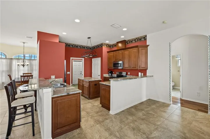 Kitchen with a kitchen bar, brown cabinets, a chandelier, a peninsula, and a kitchen island