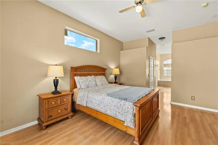 Bedroom featuring multiple windows, ensuite bathroom, light wood-style floors, and ceiling fan