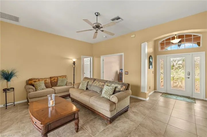 Living area with a ceiling fan, light tile patterned floors, and arched walkways