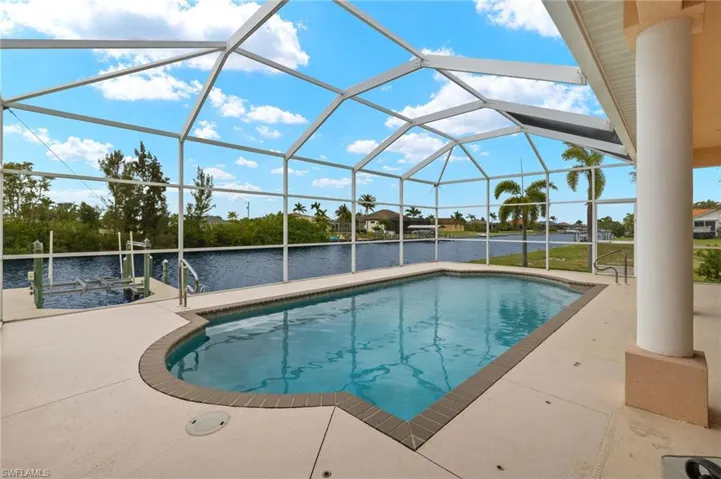 Swimming pool with a water view, a patio, glass enclosure, and a sunroom