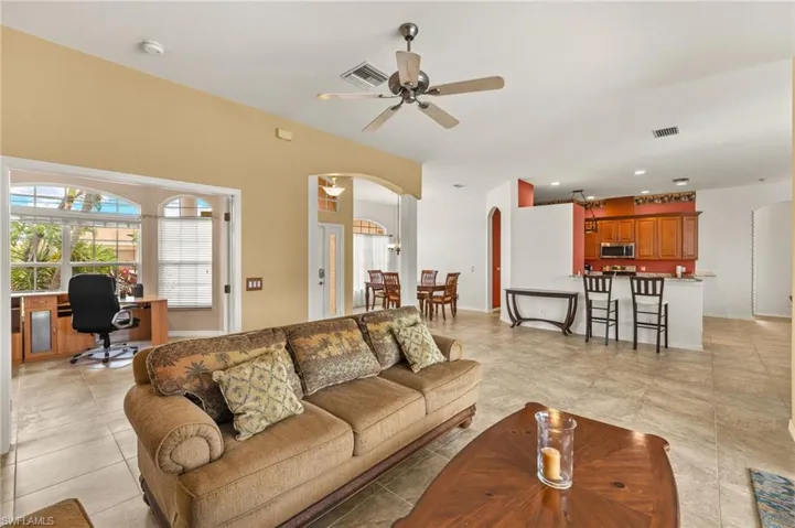 Living area with arched walkways, a desk, a ceiling fan, light tile patterned flooring, and recessed lighting