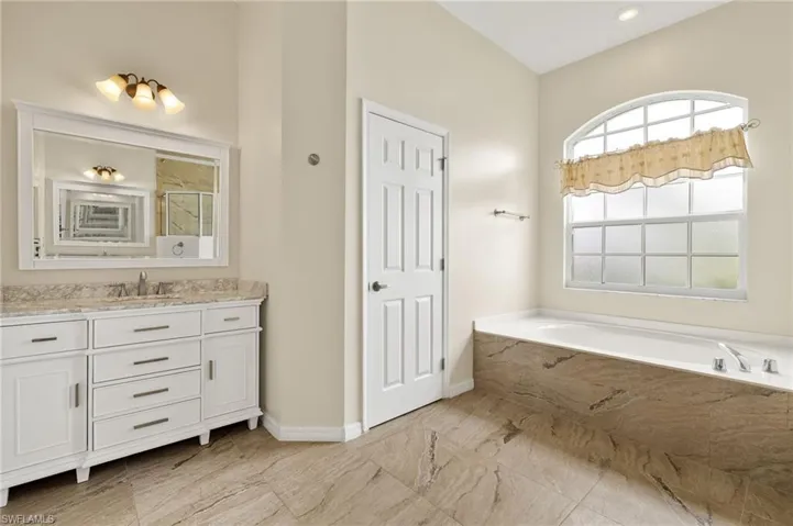 Full bath with vanity, a bath, and a marble finish shower