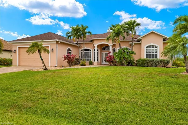 View of front of home with an attached garage, stucco siding, driveway, and a front yard