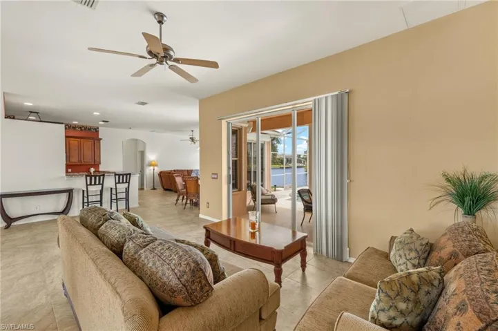 Living area with arched walkways, ceiling fan, a water view, recessed lighting, and light tile patterned floors