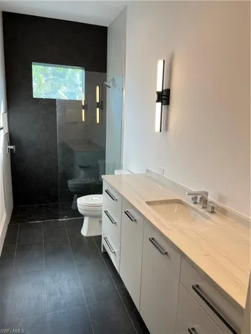 Full bathroom featuring walk in shower, vanity, and dark tile patterned floors
