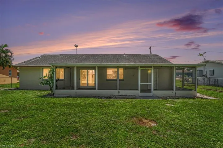 Expansive backyard featuring a screened-in lanai with a concrete slab, multiple windows, and a sliding glass door