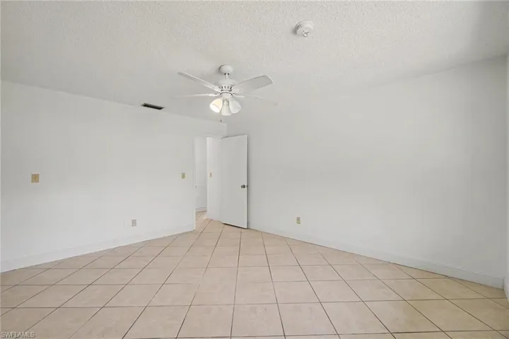 White interior walls, tile flooring, ceiling fan, and white interior doors