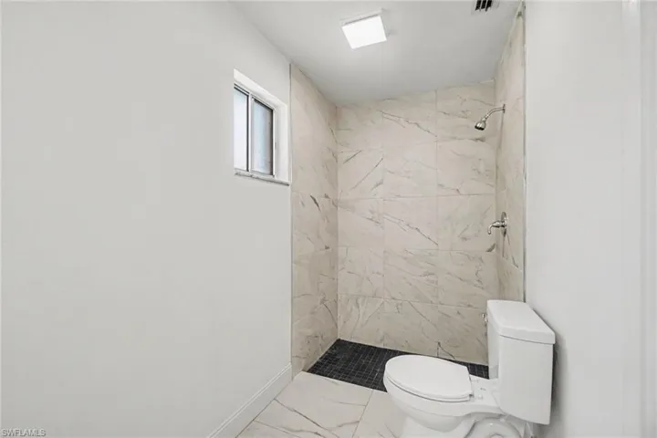 Walk-in shower with large-format tile walls, dark mosaic tile shower floor, and a chrome shower fixture