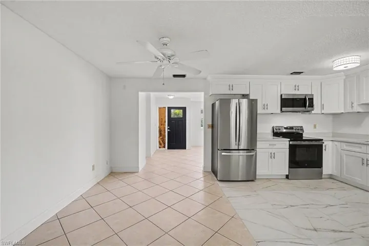 Modern kitchen with white shaker cabinetry, stainless steel appliances, and light-toned countertops