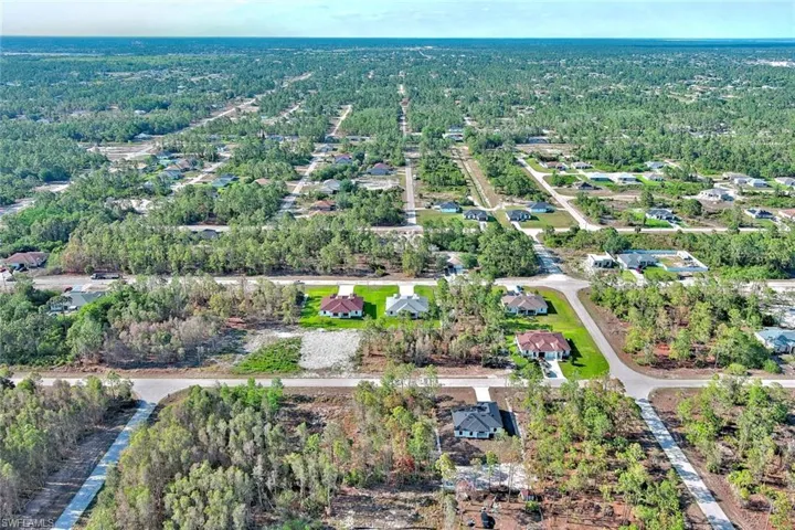 Aerial overview of property's location with nearby suburban area and a tree filled landscape