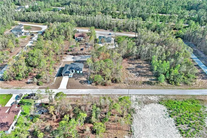 Aerial view of property and surrounding area with a heavily wooded area