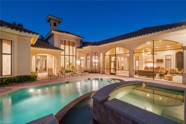 Pool at twilight with an in ground hot tub and a patio