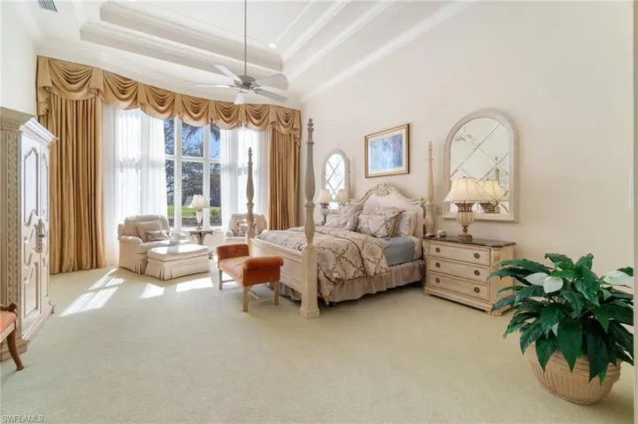 Bedroom with a tray ceiling, ornamental molding, ceiling fan, and carpet flooring