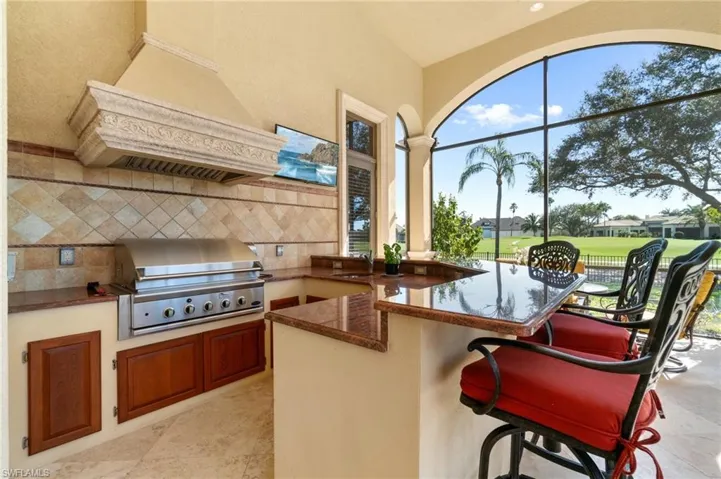 Kitchen featuring a breakfast bar, backsplash, dark stone counters, kitchen peninsula, and custom range hood