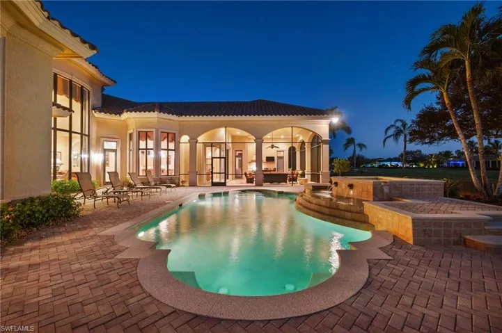 Pool at night featuring ceiling fan and a patio