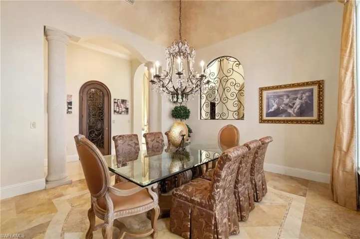 Dining area with vaulted ceiling, an inviting chandelier, and decorative columns