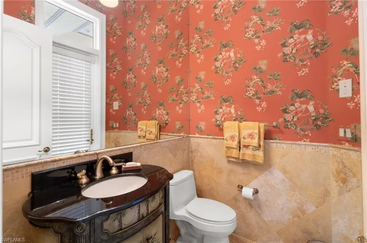 Bathroom featuring vanity, tile walls, and toilet