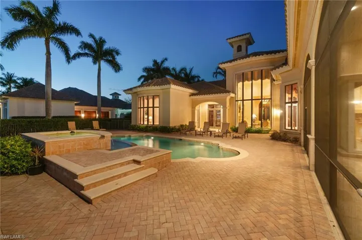 Pool at dusk featuring an in ground hot tub and a patio area